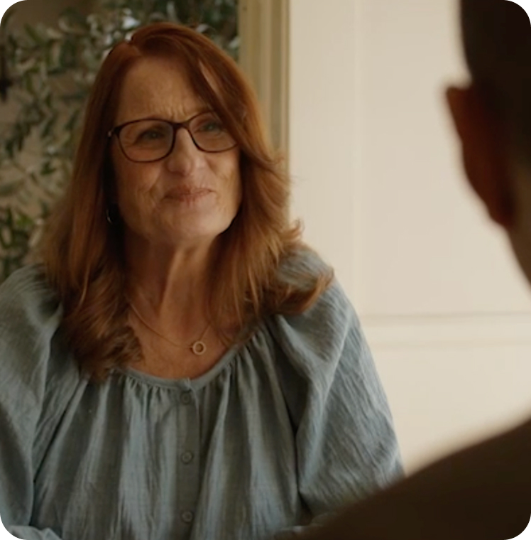 Lacey, a ZUSDURI patient, with reddish-brown hair and glasses, is shown speaking to someone.